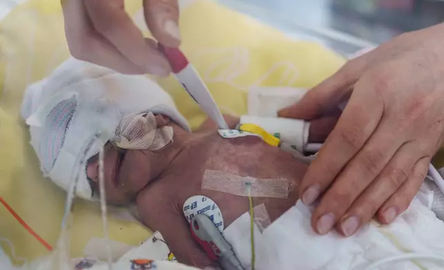 A nurse checks the temperature of a premature baby inside a temperature-controlled incubator at the regional perinatal center of Zaporizhzhia, Ukraine, Wednesday, May 6, 2026. (AP Photo/Evgeniy Maloletka)