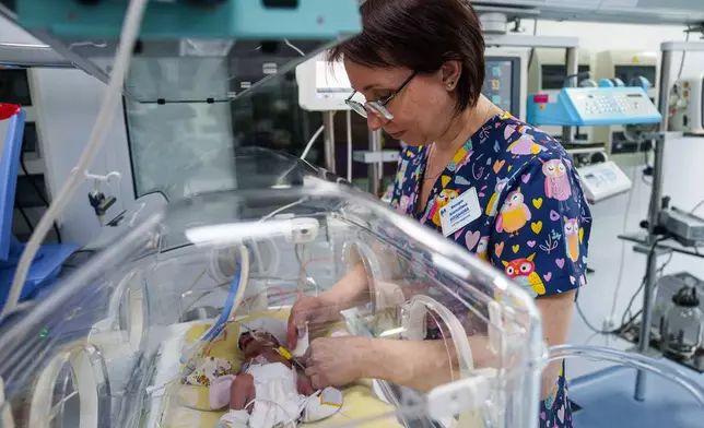 Nurse Victoria Bohdanova changes the diaper of a premature baby inside a temperature-controlled incubator at the regional perinatal center of Zaporizhzhia, Ukraine, Wednesday, May 6, 2026. (AP Photo/Evgeniy Maloletka)