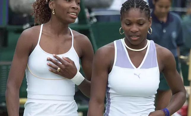 FILE -Venus Williams, left, and sister Serena talk together, during their Women's Doubles match against Irina Spirlea and Caroline Vis, at Wimbledon, July 4, 2000. (AP Photo/Alastair Grant, File)