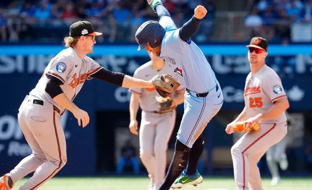 Toronto Blue Jays' George Springer, right, dodges the tag from Baltimore Orioles shortstop Gunnar Henderson (2) during a rundown in the fourth inning of a baseball game, Saturday, June 6, 2026, in Toronto. (Frank Gunn/The Canadian Press via AP)