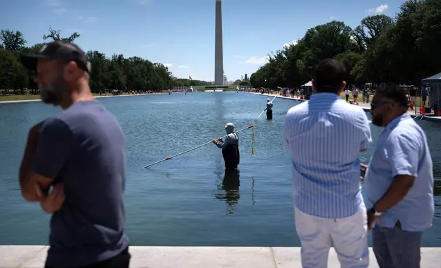 Visitors watch as National Park Service employees use vacuums to clean the Lincoln Memorial Reflecting Pool, Saturday, June 20, 2026, in Washington. (AP Photo/Mark Schiefelbein)