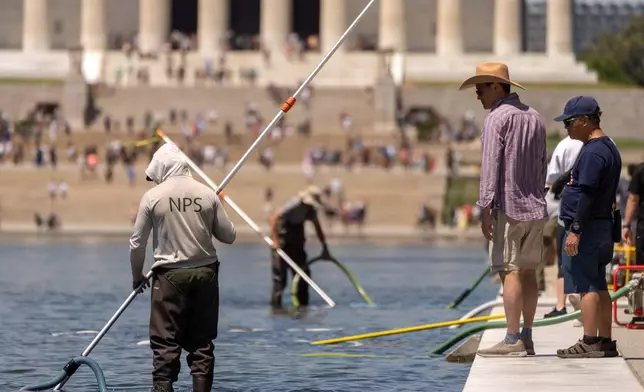 Visitors watch as National Park Service employees use vacuums to clean the Lincoln Memorial Reflecting Pool, Saturday, June 20, 2026, in Washington. (AP Photo/Mark Schiefelbein)