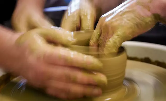 Ivan Shostak, a blind Ukrainian war veteran trains his blind comrade Viacheslav Sadovskyi to make a clay plate on a pottery wheel in a workshop at a rehabilitation center in Vinnytsia, Ukraine, on May 21, 2026. (AP Photo/Evgeniy Maloletka)