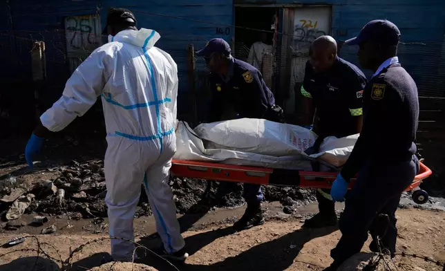 Police officers carry the body of a person on a stretcher after a mass shooting at an informal settlement in the Cleveland suburb of Johannesburg, South Africa, Wednesday, June 10, 2026. (AP Photo/Themba Hadebe)