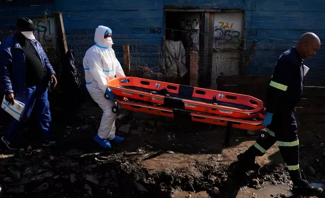 Police officers carry stretchers after a mass shooting at an informal settlement in the Cleveland suburb of Johannesburg, South Africa, Wednesday, June 10, 2026. (AP Photo/Themba Hadebe)