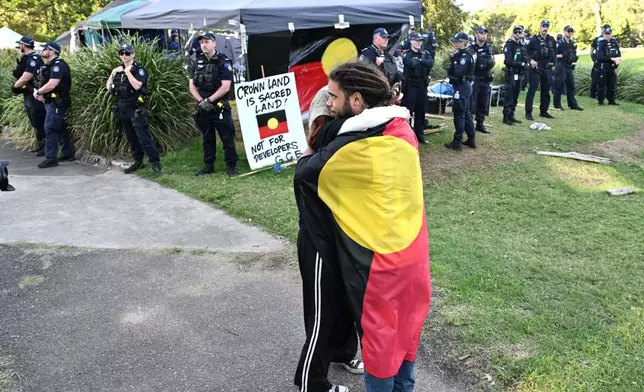 Protestors stand near a line of police as a camp site is dismantled at the construction site of the Brisbane Olympics Stadium in Brisbane, Australia, Friday, May 29, 2026. (Darren England/AAP Image via AP)