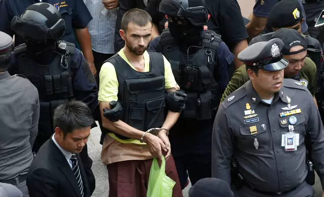 FILE - Police officers escort Bilal Mohammad, center, during a reenactment at Erawan Shrine in Bangkok, on Sept. 26, 2015. (AP Photo/Sakchai Lalit, File)