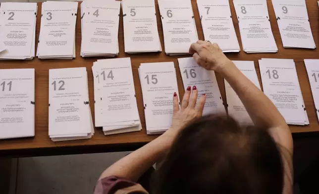 A member of an election commission prepares the ballots while waiting for voters at a polling station, during a parliamentary election in Yerevan, Armenia, Sunday, June 7, 2026. (AP Photo/Anthony Pizzoferrato)