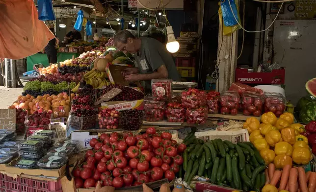 A vendor checks the fruits on his stand at a local street market following air raid sirens warning of incoming Iranian missiles in Haifa, northern Israel, Monday, June 8, 2026. (AP Photo/Leo Correa)