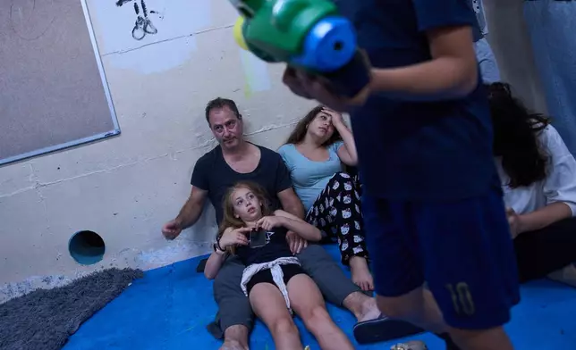People take shelter as air raid sirens warning of incoming Iranian missiles in Ramat Gan, Israel, Monday, June 8, 2026. (AP Photo/Oded Balilty)
