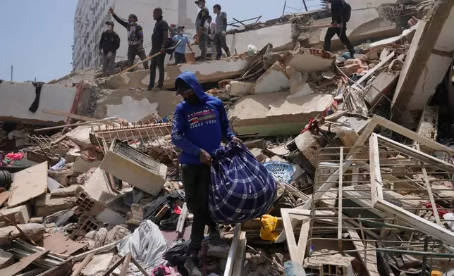 A man retrieves items from the rubble two days after earthquakes struck La Guaira, Venezuela, Friday, June 26, 2026. (AP Photo/Ariana Cubillos)