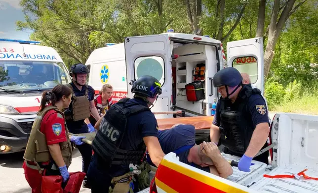 In this photo provided by the Ukrainian Emergency Services on Monday, June 29, 2026, a rescue worker with paramedics move an injured man into an ambulance after a Russian drone strike on passengers minivan in Dnipropetrovsk region, Ukraine. (Ukrainian Emergency Service via AP)