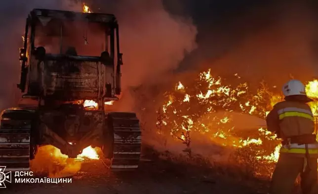 In this photo provided by the Ukrainian Emergency Services on Monday, June 29, 2026, a rescue worker puts out a fire of a tractor destroyed by a Russian strike on Mykolaiv region, Ukraine. (Ukrainian Emergency Service via AP)