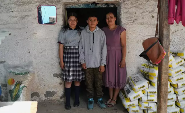 Mirsy Maricela Alva López, right, and her children, Ederson, center, and Briseidy pose for photos at their house in San Martín Cuchumatán, Guatemala, Thursday, April 30, 2026. (AP Photo/Moises Castillo)