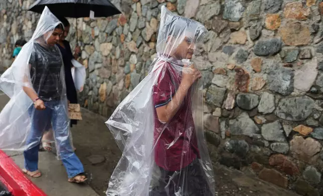 Ederson Galicia Alva, right, walks with his mother, Mirsy Maricela Alva López, and sister, Briseidy, through the historic center of Guatemala City, Wednesday, May 27, 2026. (AP Photo/Moises Castillo)