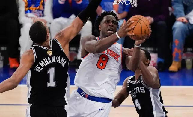 New York Knicks forward Og Anunoby (8) shoots between San Antonio Spurs forward Victor Wembanyama (1) and guard De'aaron Fox (4) during the first half of Game 4 of the NBA Finals basketball series, Wednesday, June 10, 2026, in New York. (AP Photo/Ross D. Franklin)