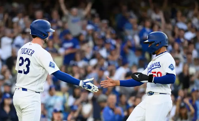 Los Angeles Dodgers' Mookie Betts, right, celebrates with Kyle Tucker, left, after scoring on a two-run single hit by Max Muncy during the first inning of a baseball game against the Baltimore Orioles in Los Angeles, Friday, June 19, 2026. (AP Photo/Kyusung Gong)