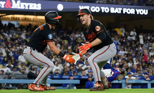 Baltimore Orioles' Gunnar Henderson, right, celebrates his two-run home run with Jackson Holliday during the sixth inning of a baseball game against the Los Angeles Dodgers in Los Angeles, Friday, June 19, 2026. (AP Photo/Kyusung Gong)