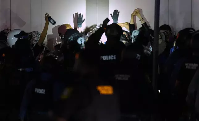 Protesters raise their hands as law enforcement officers surround them outside Delaney Hall detention center Sunday, May 31, 2026, in Newark, N.J. (AP Photo/Adam Gray)