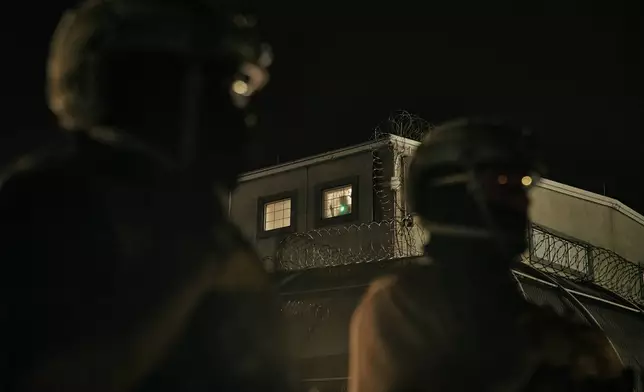 A detained migrant has a laser pointed at him as he stands by the window while ICE agents stand guard outside the Delaney Hall detention center during a protest near the entrance gates, Wednesday, May 27, 2026, in Newark, N.J. (AP Photo/Andres Kudacki)