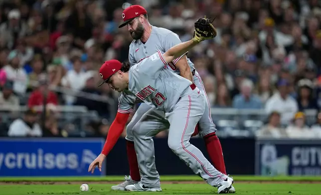 Cincinnati Reds first baseman Sal Stewart, front, drops the ball before throwing to first too late as San Diego Padres' Jase Bowen arrives safely for a bunt single while Cincinnati Reds pitcher Tejay Antone looks on, behind, during the seventh inning of a baseball game Monday, June 8, 2026, in San Diego. (AP Photo/Gregory Bull)