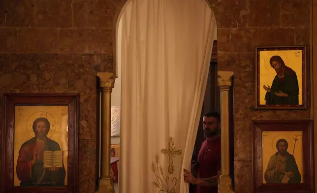 A church caretaker opens a curtain inside St. George Greek Orthodox Church in the southern town of Marjayoun, Lebanon, Wednesday, June 10, 2026. (AP Photo/Hassan Ammar)