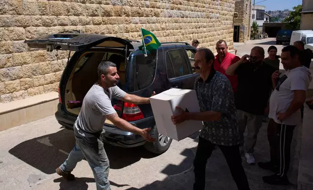 Residents unload donated supplies for local families in the southern village of Qlayaa, Lebanon, Friday, June 12, 2026. (AP Photo/Hassan Ammar)