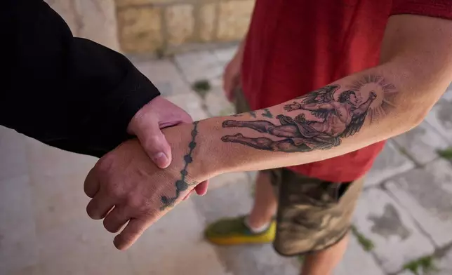 A man displays a Christian tattoo depicting an angel on his arm outside St. Georges Orthodox Church in the southern town of Marjayoun, Lebanon, Wednesday, June 10, 2026. (AP Photo/Hassan Ammar)