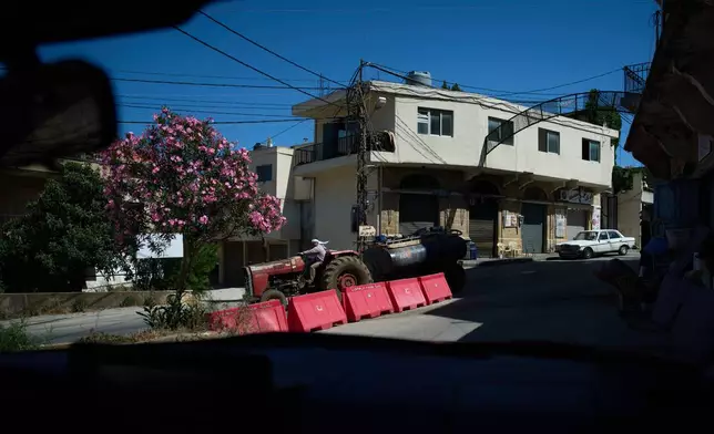 A farmer drives a tractor carrying a water tank through the southern town of Marjayoun, Lebanon, Wednesday, June 10, 2026. (AP Photo/Hassan Ammar)