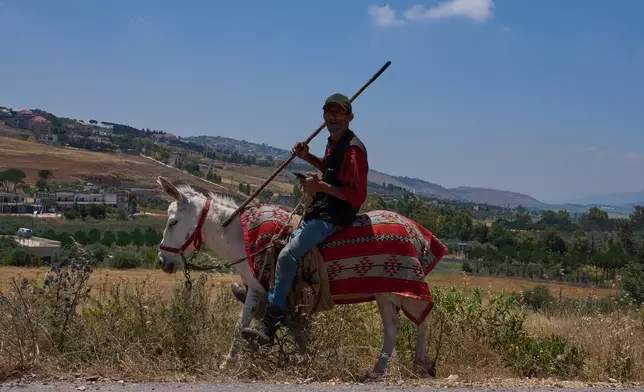 A farmer rides a donkey along a road in the village of Dibbine, southeast Lebanon, Thursday, June 11, 2026. (AP Photo/Hassan Ammar)
