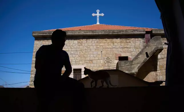 A man sits with a cat outside St. Georges Orthodox Church in the southern town of Marjayoun, Lebanon, Wednesday, June 10, 2026. (AP Photo/Hassan Ammar)