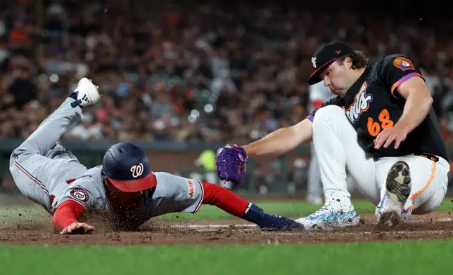 Washington Nationals' Jacob Young, left, slides home safe on a wild pitch as San Francisco Giants pitcher Erik Miller (68) applies the tag during the seventh inning of a baseball game in San Francisco, Tuesday, June 9, 2026. (AP Photo/Jed Jacobsohn)