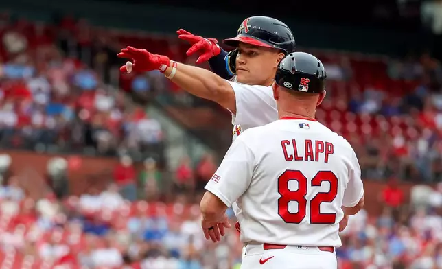 St. Louis Cardinals' JJ Wetherholt, left, gestures toward the dugout while first base coach Stubby Clapp (82) stands nearby after hitting a single during the first inning of a baseball game against the Chicago Cubs, Sunday, May 31, 2026, in St. Louis. (AP Photo/Scott Kane)