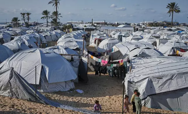 Palestinian children walk between tents at an orphanage camp in Khan Younis, southern Gaza Strip, Tuesday, Jan. 20, 2026. (AP Photo/Jehad Alshrafi)