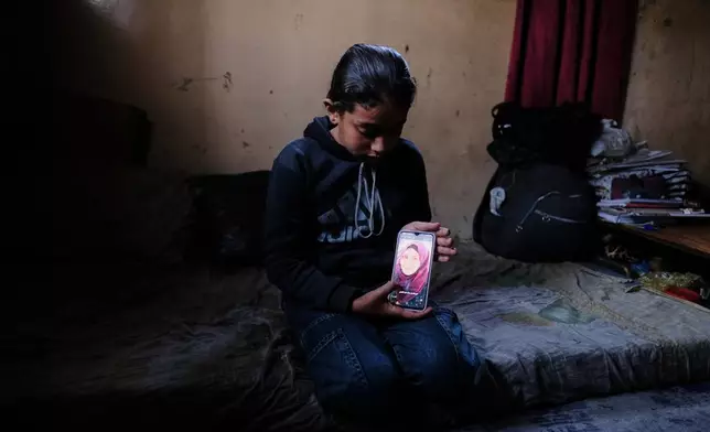 Eleven-year-old Ghazal al-Kibritti, who lost her parents and three siblings in an Israeli airstrike, poses with a photo of her mother, Sana, at her grandparents' home in Gaza City, Sunday, April 26, 2026. (AP Photo/Jehad Alshrafi)