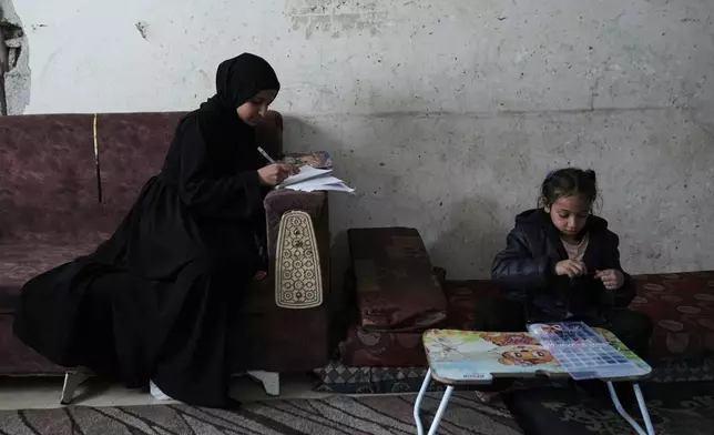 Raghad Ramzi Al-Ajal, who lost her parents in an Israeli airstrike, studies at the Gaza City home where she lives with relatives, Monday, Jan. 19, 2026. (AP Photo/Jehad Alshrafi)