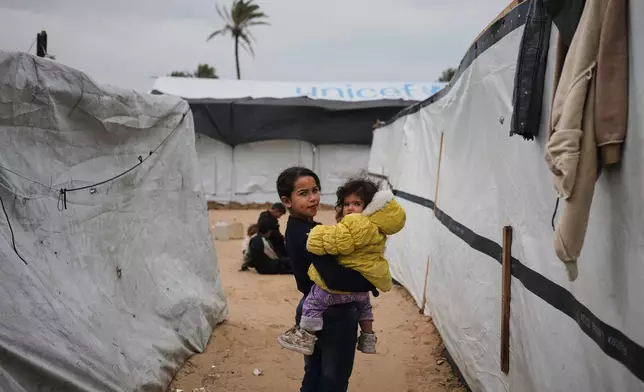 Palestinian children walk between tents at an orphanage camp in Khan Younis, southern Gaza Strip, Thursday, Jan. 22, 2026. (AP Photo/Jehad Alshrafi)