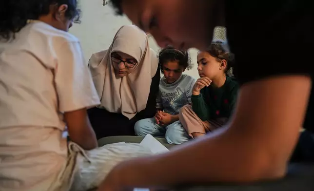 Ikhlas al-Kafarna, 35, teaches her orphaned nieces and nephews at her home in Gaza City, May 31, 2026. The children lost their parents in an Israeli airstrike. (AP Photo/Abdel Kareem Hana)