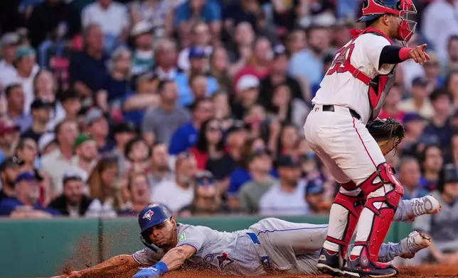 Toronto Blue Jays' Andrés Giménez, left, scores on a ground out by Vladimir Guerrero Jr., as Boston Red Sox catcher Mickey Gasper signals the throw to go to first, during the third inning of a baseball game, Wednesday, June 17, 2026, in Boston. (AP Photo/Charles Krupa)