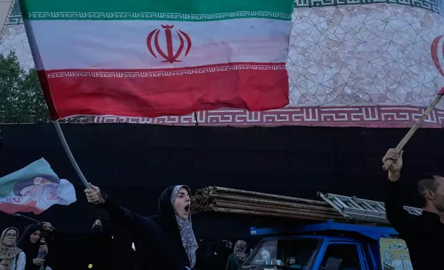 A woman waves an Iranian flags as she chants slogans against Iran and U.S. talks at the Islamic Revolution square in Tehran, Iran, Sunday, June 14, 2026. (AP Photo/Vahid Salemi)
