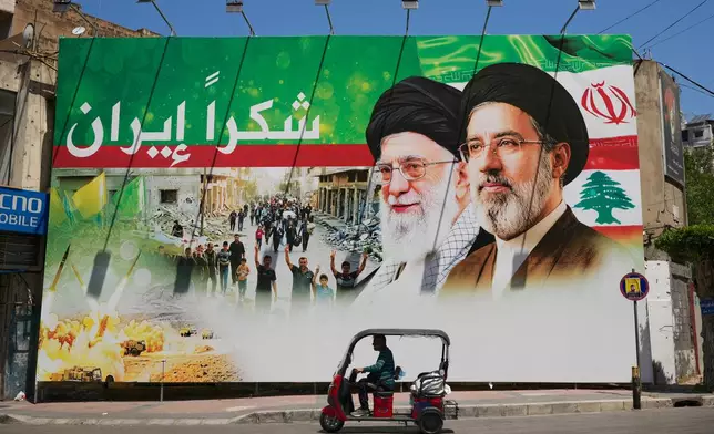 A man rides a scooter past a giant billboard that shows the late Iranian leader Ayatollah Ali Khamenei, center, and Iranian Supreme Leader Ayatollah Mojtaba Khamenei, with Arabic writing that reads: "Thank you Iran", in Dahiyeh, Beirut's southern suburbs, Lebanon, Monday, June 15, 2026. (AP Photo/Hussein Malla)