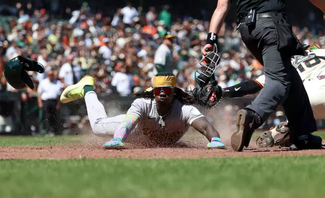 Athletics' Lawrence Butler, center, slides home safe in front of San Francisco Giants catcher Eric Haase (18) on a single hit by Jeff McNeil during the eighth inning of a baseball game in San Francisco, Thursday, June 25, 2026. (AP Photo/Jed Jacobsohn)