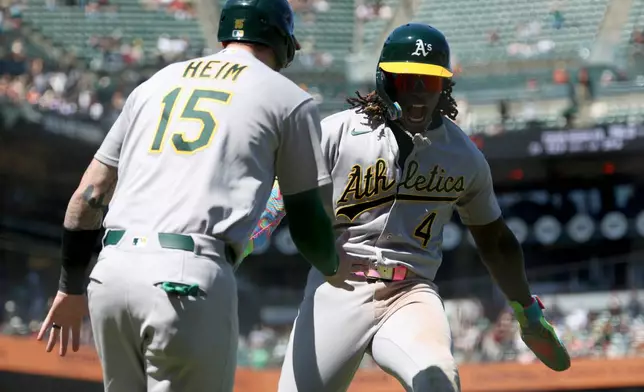 Athletics' Lawrence Butler (4) celebrates with Jonah Heim (15) after scoring on a single by Max Muncy during the ninth inning of a baseball game against the San Francisco Giants in San Francisco, Thursday, June 25, 2026. (AP Photo/Jed Jacobsohn)