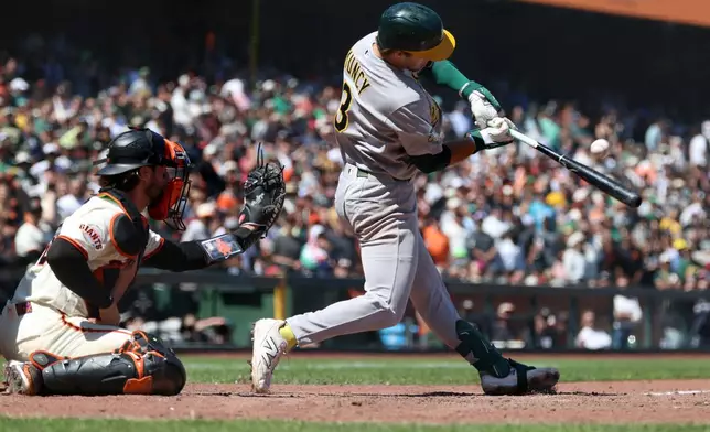 Athletics' Max Muncy, right, hits a two-run single in front of San Francisco Giants catcher Eric Haase, left, during the ninth inning of a baseball game in San Francisco, Thursday, June 25, 2026. (AP Photo/Jed Jacobsohn)