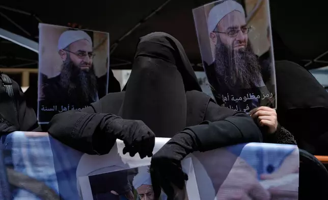 FILE - Amal Shamseddine, the wife of imprisoned Sunni cleric Ahmad al-Assir, holds a portrait of her husband during a protest against the clause in a proposed amnesty law that would exclude her husband from being eligible for amnesty, after Friday prayers in Beirut, Lebanon, Friday, May 22, 2026. (AP Photo/Bilal Hussein, File)