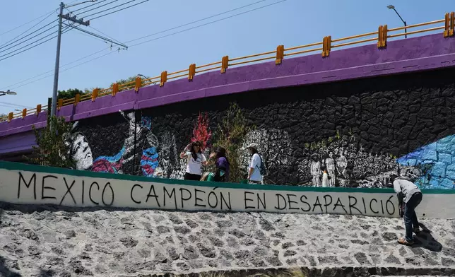 A person protesting the more than the 134,000 disappeared people, writes in spray paint, "Mexico, champion of disappearances" as Mexico prepares to host the 2026 FIFA World Cup in Mexico City, Saturday, May 30, 2026. (AP Photo/Marco Ugarte)