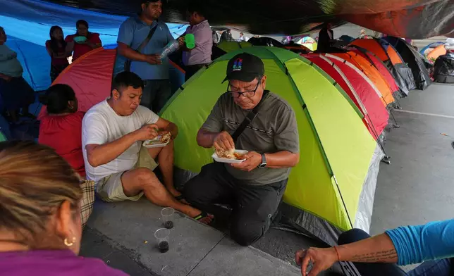 Teachers eat by tents they set up during protests to demand salary increases in Mexico City, Tuesday, June 2, 2026. (AP Photo/Marco Ugarte)