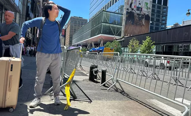 A traveler tries to navigate the area as stringent security measures are set up outside of Madison Square Garden in New York, Monday, June 8, 2026, as President Donald Trump is set to attend Game 3 of the NBA Finals basketball series between the New York Knicks and the San Antonio Spurs. (AP Photo/Ted Shaffrey)