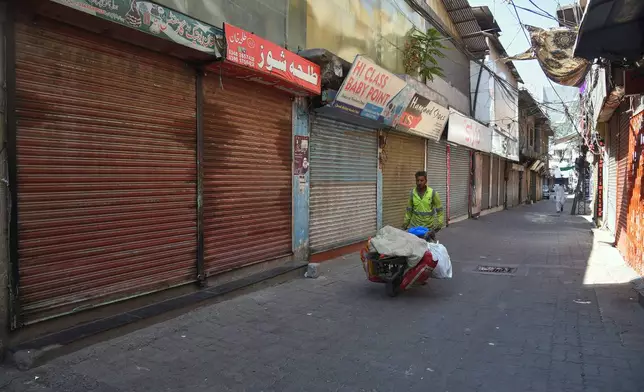 Local residents walk through a closed market during a strike called by an outlawed alliance of activist groups "Joint Awami Action Committee" (JAAC) demanding greater political rights and the abolition of 12 legislative refugee seats, in Muzaffarabad, the capital of Pakistan-administered Kashmir, Tuesday, June 9, 2026. (AP Photo/M.D. Mughal)