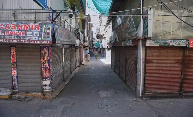 Local residents walk through a closed market during a strike called by an outlawed alliance of activist groups "Joint Awami Action Committee" (JAAC) demanding greater political rights and the abolition of 12 legislative refugee seats, in Muzaffarabad, the capital of Pakistan-administered Kashmir, Tuesday, June 9, 2026. (AP Photo/M.D. Mughal)
